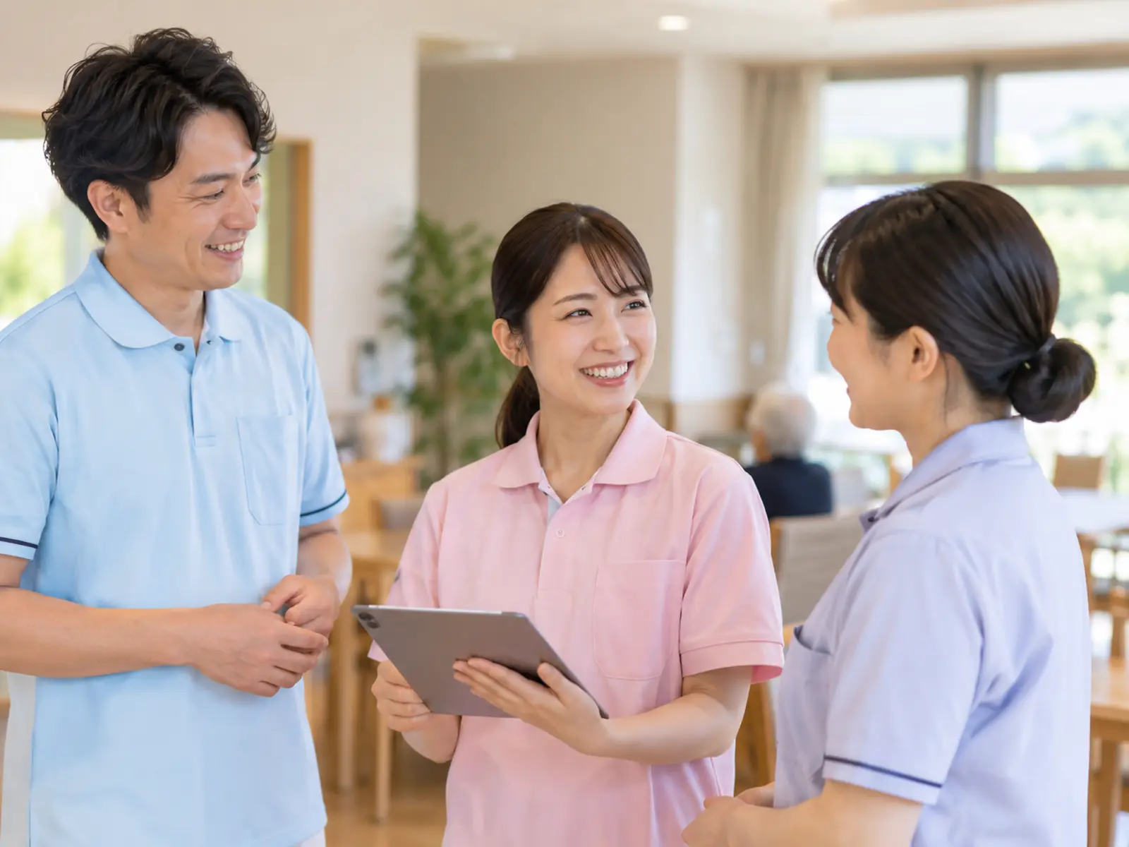 施設のフロアで、職員がタブレットを手に立ち話をしている様子